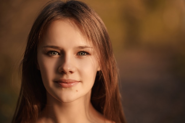 Retrato de mulher jovem sorridente no parque outono com folhas amarelas