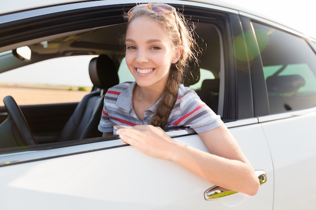 Retrato de mulher jovem sorridente, olhando pela janela de seu carro