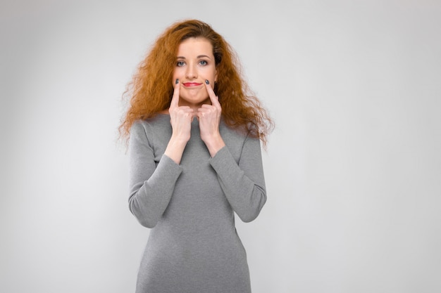 Retrato de mulher jovem triste ruiva triste chateada em roupas cinza, expressando tristeza em fundo cinza