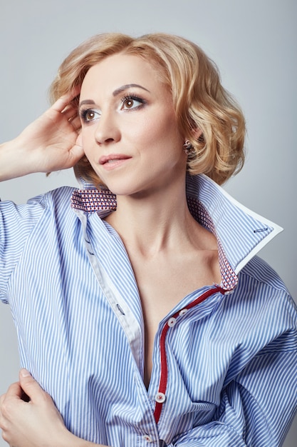 Retrato de mulher loira de camisa azul, corpo nu, figura de menina perfeita, aparência sensual, imagem atrevida, mulher em cubo branco