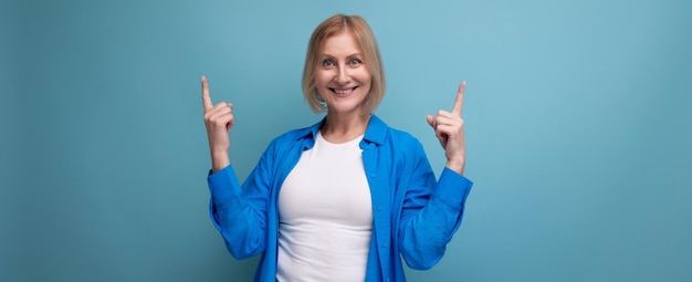 Retrato de mulher loira positiva em camisa azul elegante em fundo de estúdio