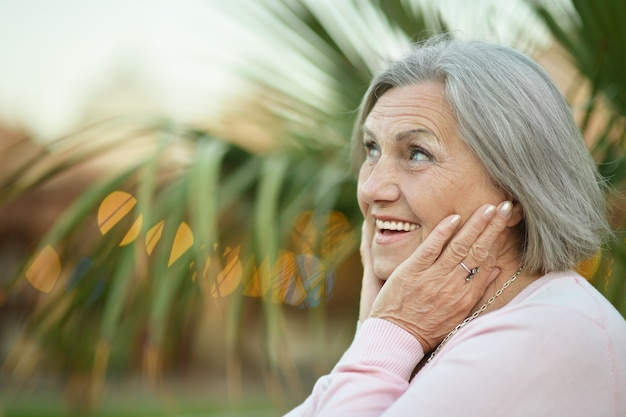 Retrato de mulher madura sorridente no fundo de flores desfocadas