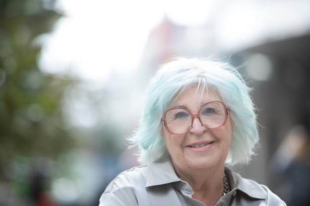 Retrato de mulher mais velha com cabelo de moda olhando para câmera com sorriso ao ar livre