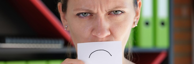 Foto retrato de mulher mal-humorada cobrindo o rosto com símbolo de emoticon infeliz de papel chateado rosto infeliz