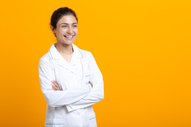 Retrato de mulher médico indiano em vestido médico branco, isolado no fundo amarelo.
