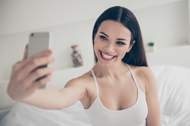 retrato de mulher morena na cama com telefone