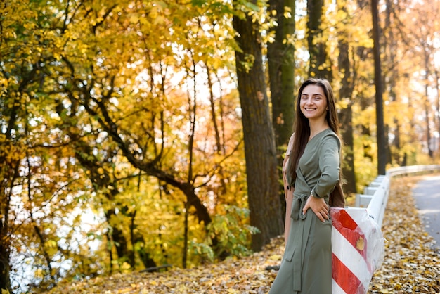 Retrato de mulher morena no parque outono com vestido verde-oliva