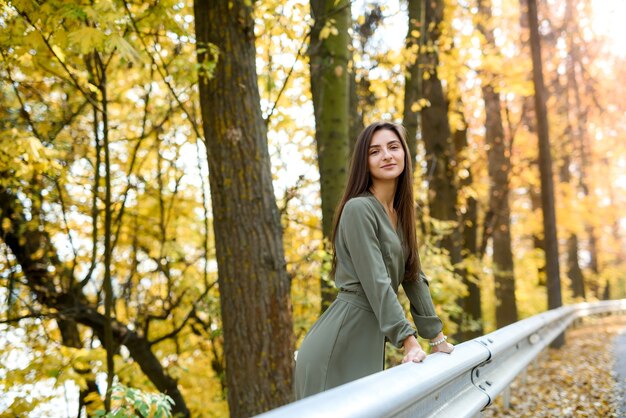 Retrato de mulher morena no parque outono com vestido verde-oliva