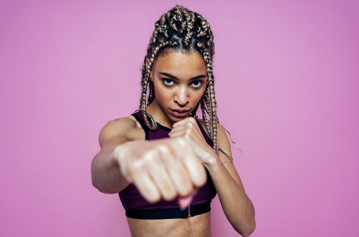Foto retrato de mulher mostrando punho contra fundo colorido