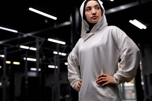 Retrato de mulher muçulmana esportiva séria posando para a câmera olhando para o lado no ginásio. em hijab branco. conceito de esporte