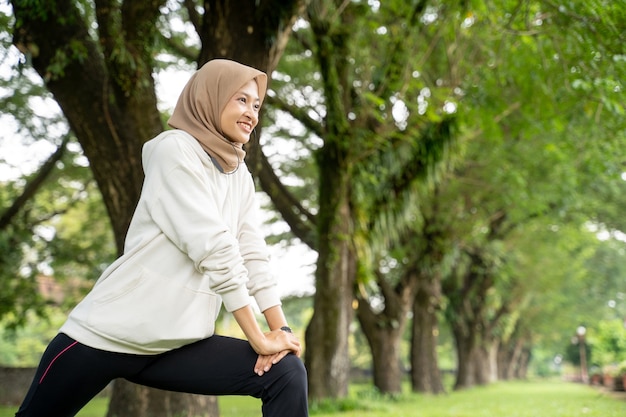 Retrato de mulher muçulmana feliz e divertida fazendo exercícios ao ar livre pela manhã