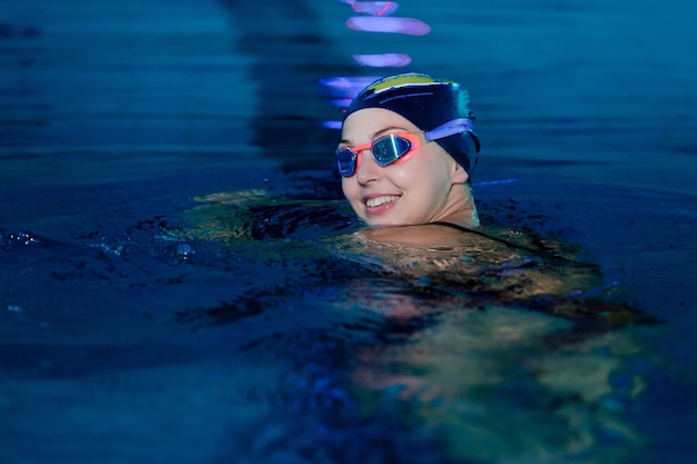 Retrato de mulher nadando com boné e óculos na piscina