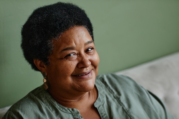 Foto retrato de mulher negra sênior sorrindo para a câmera contra fundo verde em casa, copie o espaço