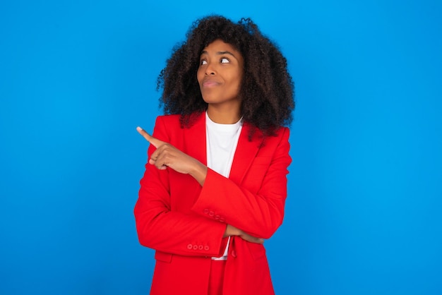 Retrato de mulher posando na câmera com aparência complicada apresentando produto com o dedo indicador