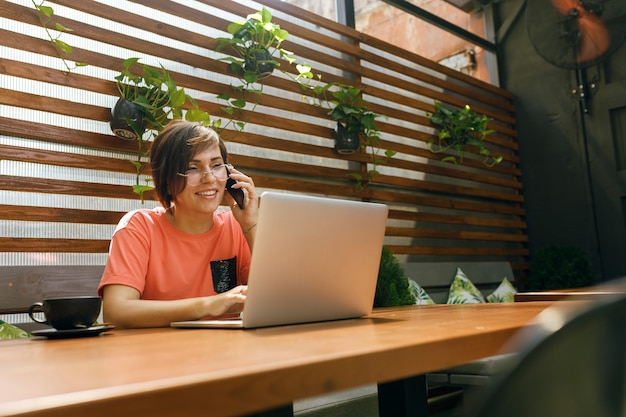 retrato de mulher profissional madura confiante sentada na esplanada de um café, usando um laptop