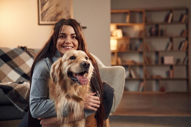 Retrato de mulher que está com cachorro golden retriever em casa