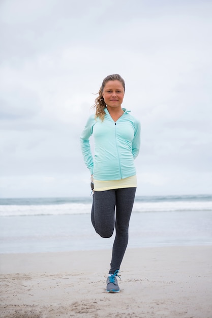 Retrato de mulher realizando exercícios de alongamento na praia