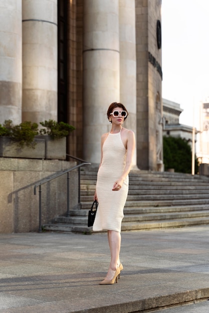 Foto retrato de mulher rica ao ar livre com vestido elegante e óculos de sol