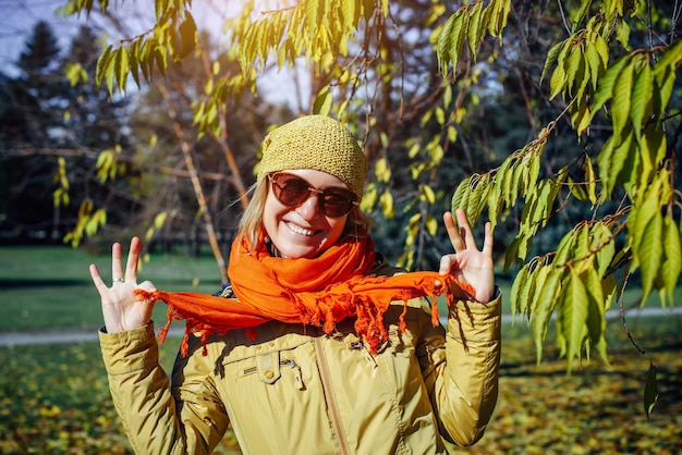 Retrato de mulher rindo no fundo de árvores de outono. Atividades ao ar livre na floresta ensolarada de outono. Conceito de estilo de vida feliz.