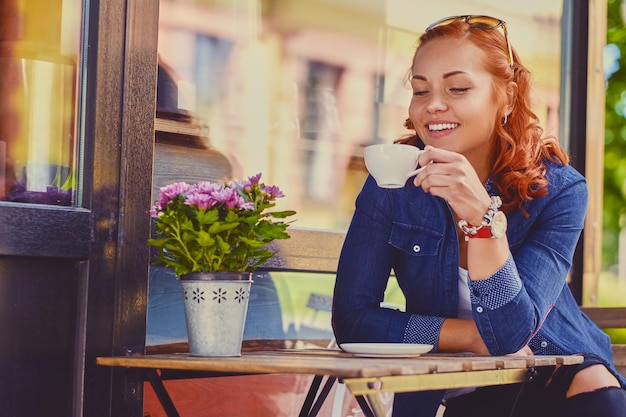 Retrato de mulher ruiva atraente bebe café em um café.