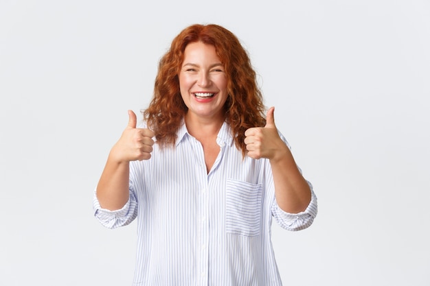 Foto retrato de mulher satisfeita mostrando o polegar para cima em aprovação, como produto, garantia de qualidade