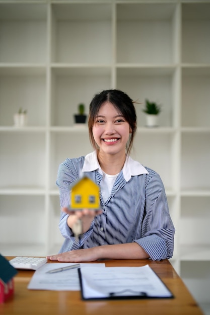 Retrato de mulher segurando o modelo de casa na mão contrato de contrato para compra de propriedade