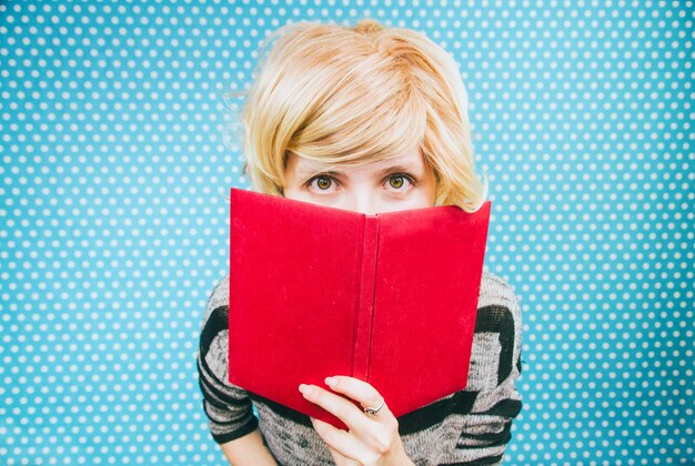 Foto retrato de mulher segurando um livro vermelho contra uma parede de pontos azuis