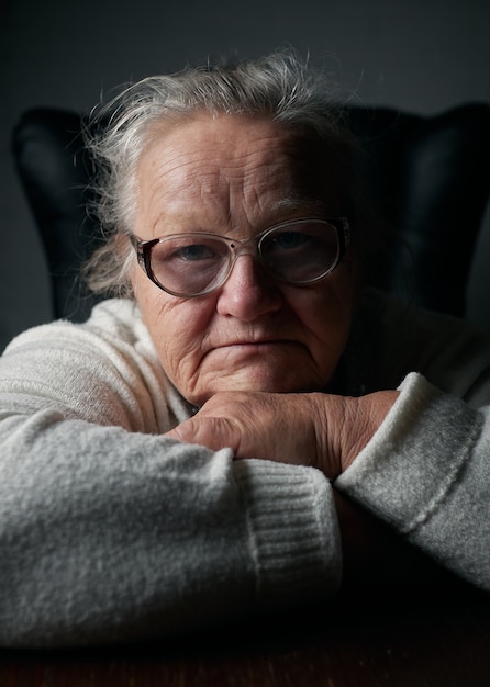 Retrato de mulher sênior em vidro em fundo escuro