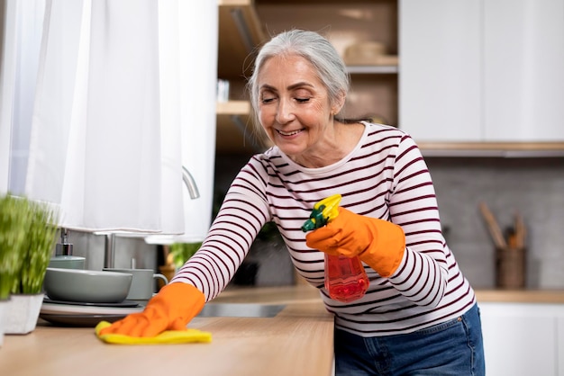 Retrato de mulher sênior sorridente fazendo limpeza na cozinha