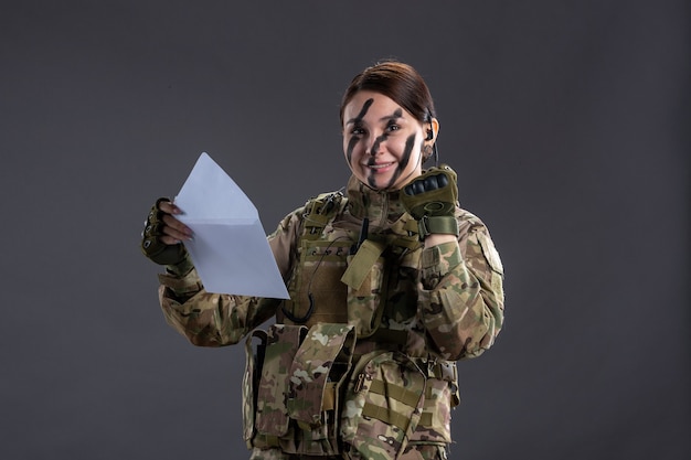 Retrato de mulher soldado lendo carta na parede escura