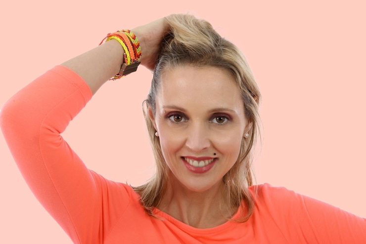 Foto retrato de mulher sorridente com a mão no cabelo contra um fundo colorido