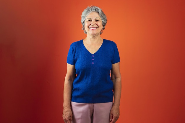 Retrato de mulher sorridente com cabelos grisalhos e camiseta azul isolado sobre fundo laranja