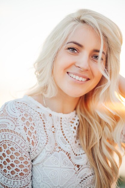 Foto retrato de mulher sorridente com cabelos loiros contra o céu claro