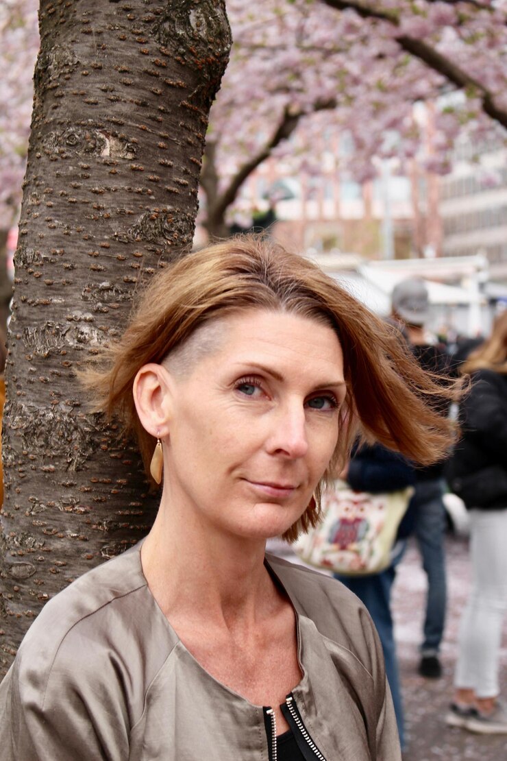 Foto retrato de mulher sorridente contra o tronco de uma árvore
