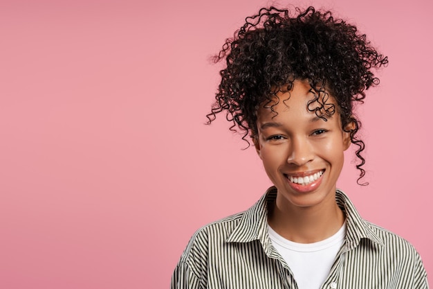 Retrato de mulher sorridente e alegre com cabelos ondulados olhando para a câmera de pé isolada