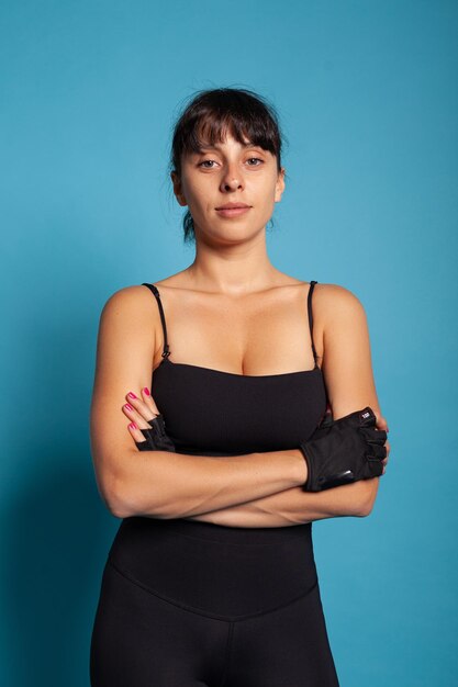 Retrato de mulher sorridente em forma de sportwear em estúdio com fundo azul durante o treino esportivo. Personal trainer esticando os músculos do corpo praticando exercícios trabalhando no estilo de vida saudável