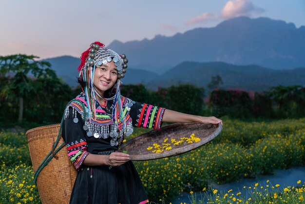 Retrato de mulher sorridente em roupas tradicionais segurando uma cesta de vime enquanto estava em uma fazenda