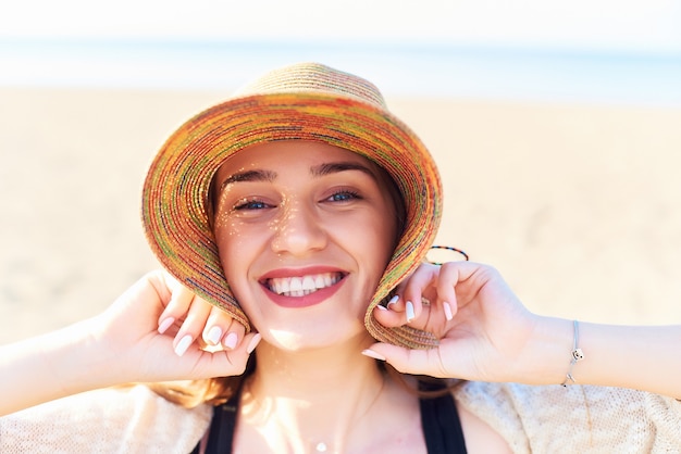 Retrato, de, mulher sorridente, ligado, praia, desgastar, chapéu palha