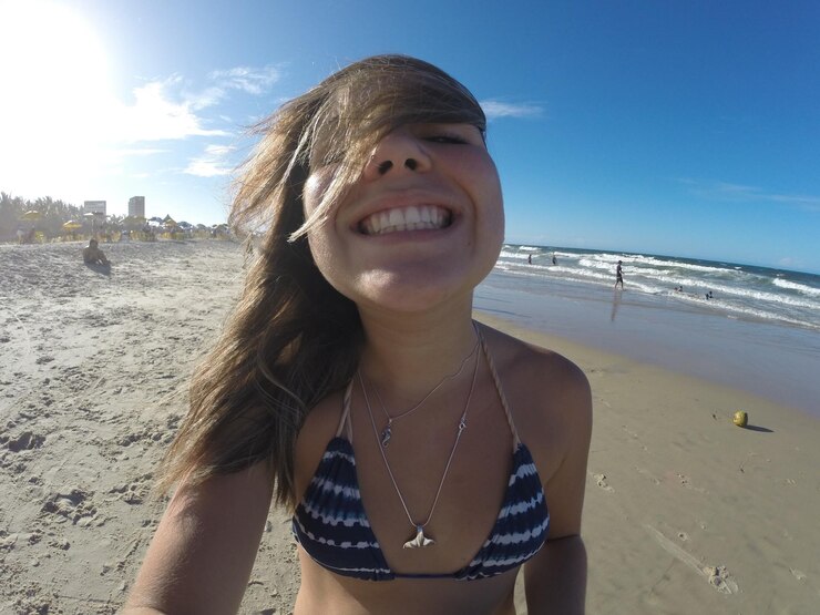 Foto retrato de mulher sorridente na praia contra o céu