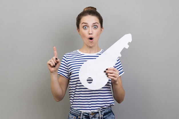 Foto retrato de mulher sorridente segurando papel enquanto está de pé contra a parede