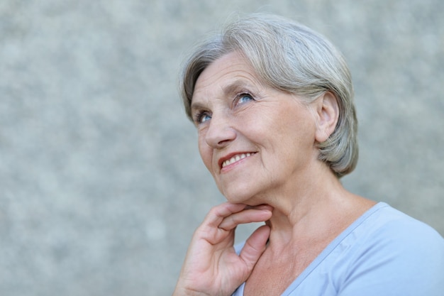 Retrato de mulher sorridente sênior em um fundo cinza