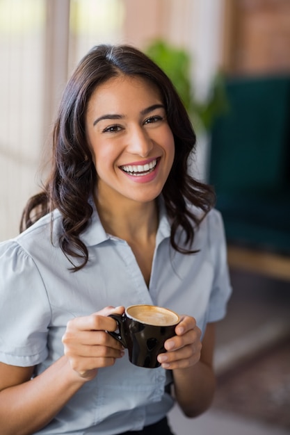 Retrato de mulher sorridente tomando café