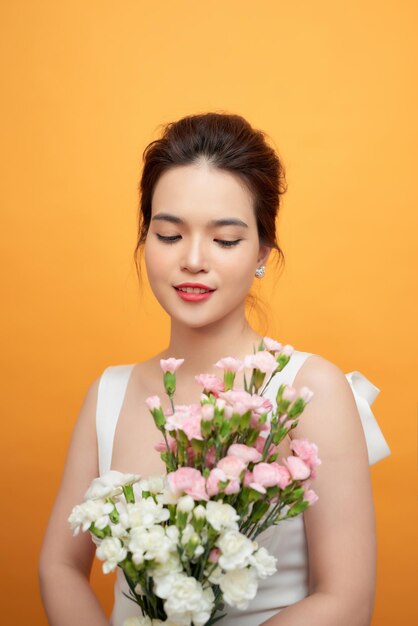 Retrato de mulher surpresa olhando buquê floral nas mãos isoladas em amarelo