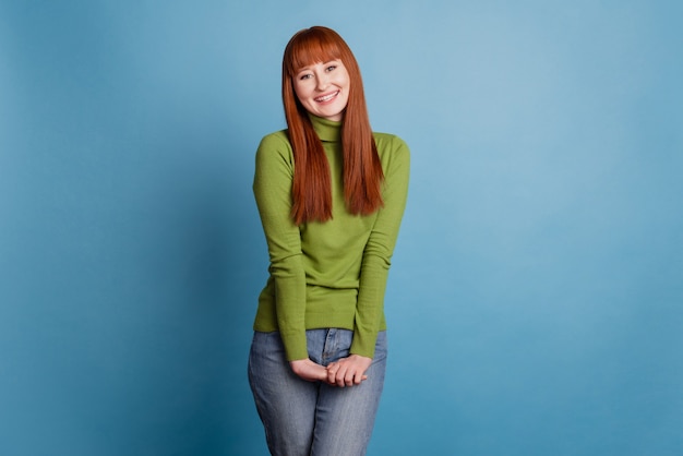 Retrato de mulher tímida sorrindo em pé isolado sobre fundo azul