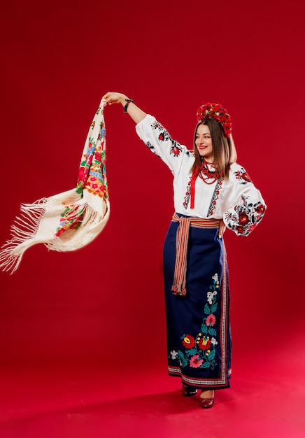 Retrato de mulher ucraniana em roupas étnicas tradicionais e grinalda vermelha floral com lenço no fundo do estúdio magenta viva Chamada de vestido bordado nacional ucraniano vyshyvanka