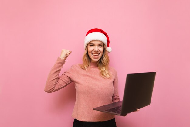 retrato de mulher usando chapéu de Papai Noel com laptop