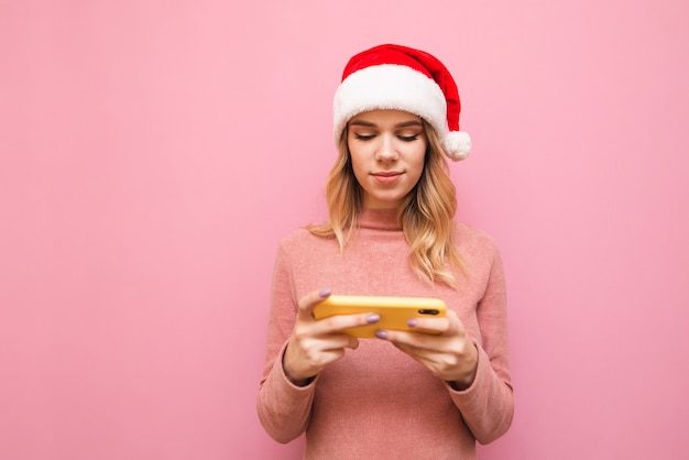 retrato de mulher usando chapéu de Papai Noel com telefone