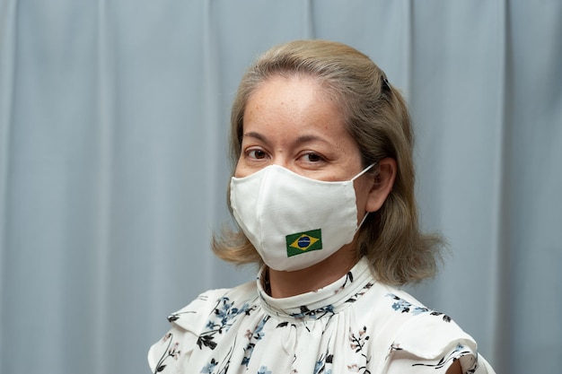 Retrato de mulher usando máscara cirúrgica com bandeira do Brasil