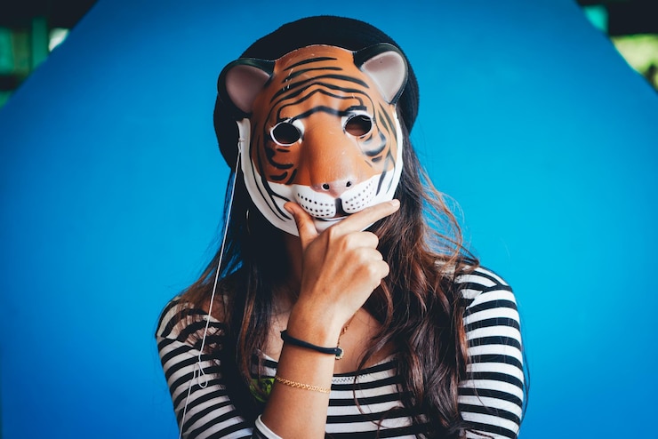 Foto retrato de mulher usando máscara de tigre contra a parede azul