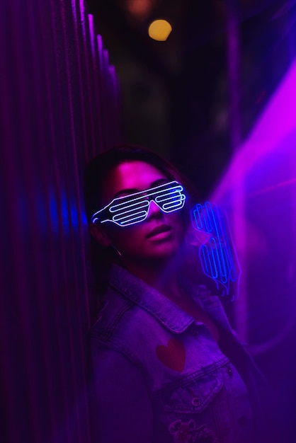 Retrato de mulher usando óculos de sol iluminados em uma boate